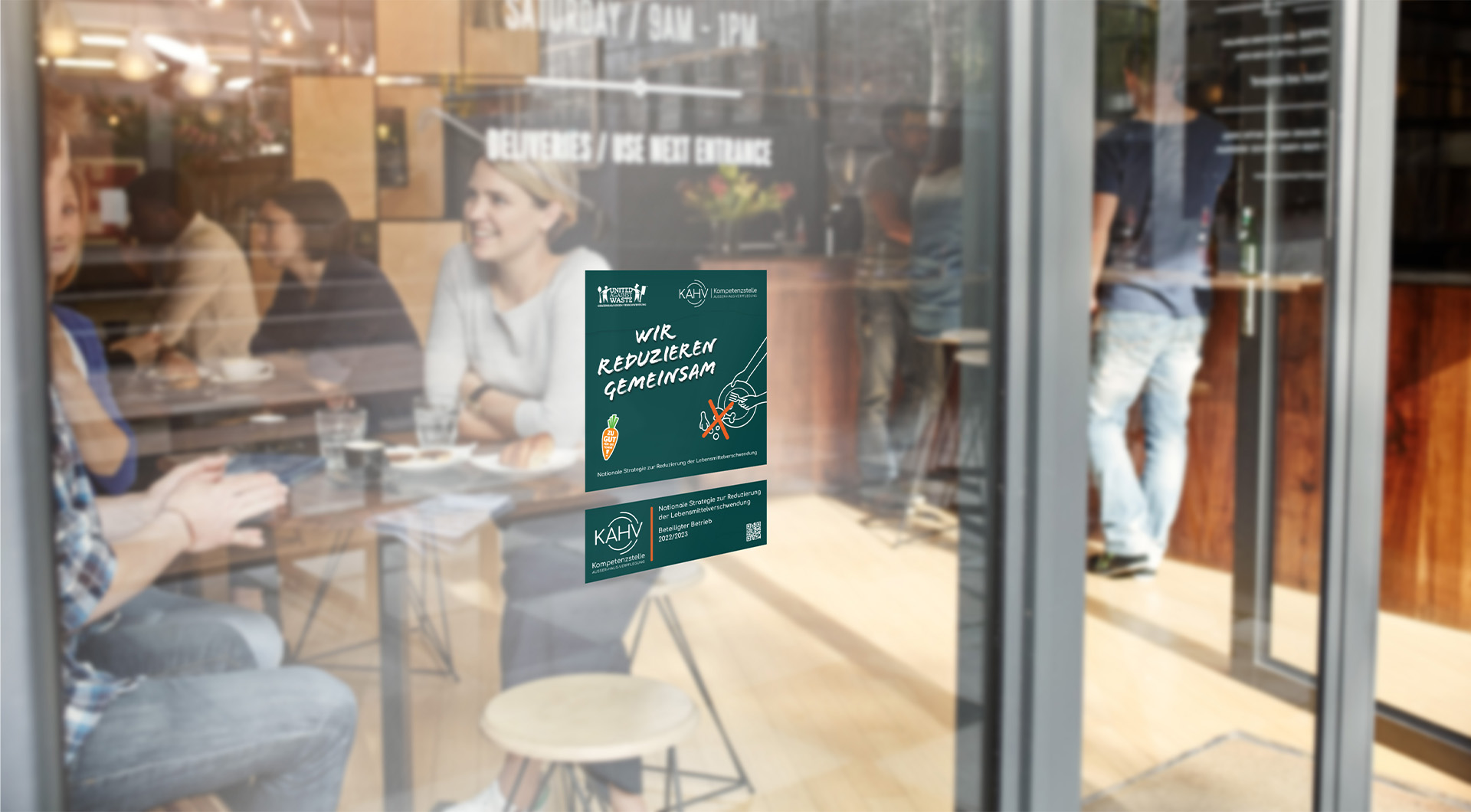 Eine Glasscheibe, im Hintergrund Gäste in einem Restaurant, auf der Glasscheibe ein Aufkleber mit dem KAHV-Zertifikat-Sticker
