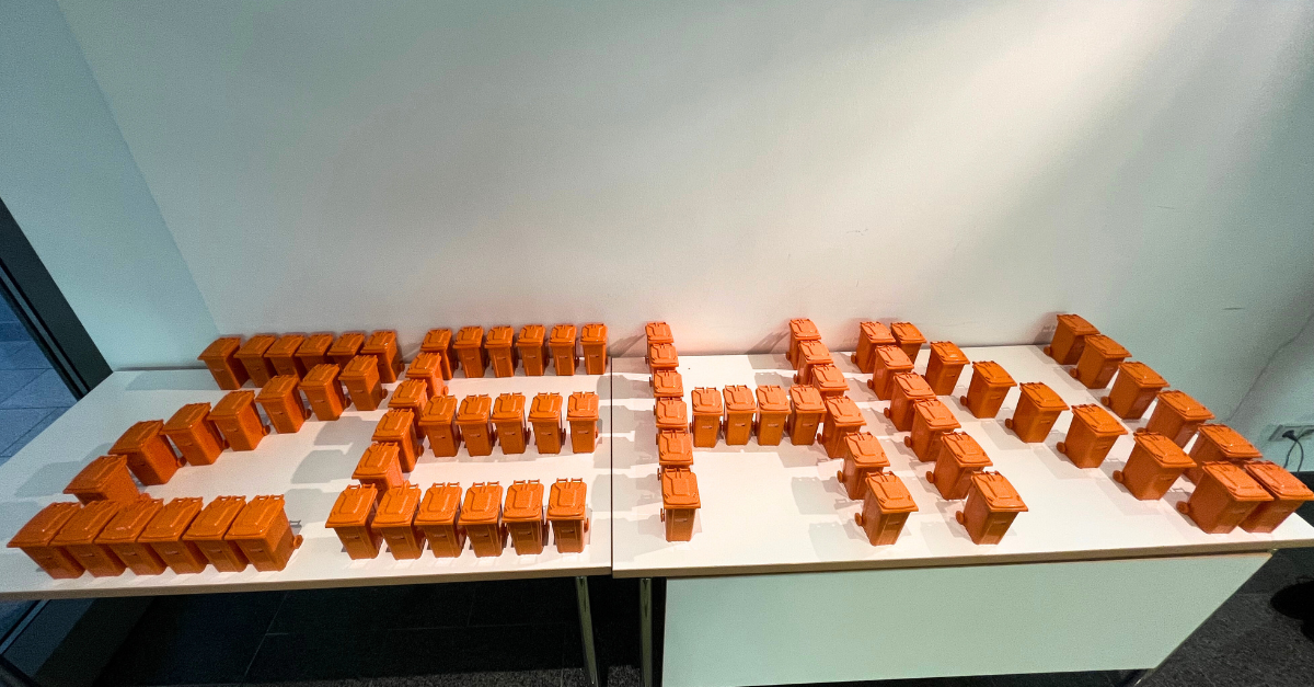 Das Wort Zehn aus orangenen Miniatur-Mülltonnen gestellt